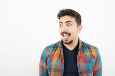 Damalı tişörtlü, dili dışarı çıkmış genç ve yakışıklı bir adam resmi. Yüksek kalite fotoğraf