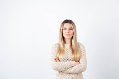 Beyaz duvara yaslanmış kolları çapraz duran güzel bir kadın resmi. Yüksek kalite fotoğraf