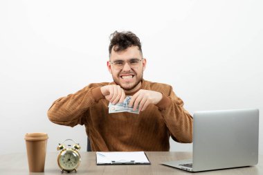 Genç muhasebeci masasında oturuyor ve para gösteriyor. Yüksek kalite fotoğraf