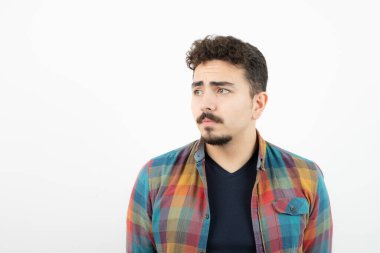 Kareli tişört giymiş ve beyaz duvarın üzerinde duran yakışıklı bir adam resmi. Yüksek kalite fotoğraf