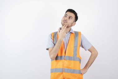 Güvenlik yeleği giymiş genç bir mühendisin bir şey düşündüğü portresi. Yüksek kalite fotoğraf