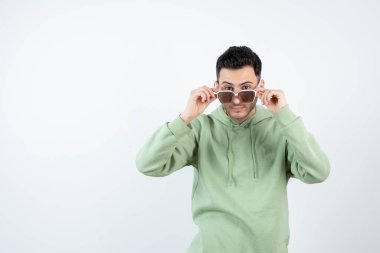 Gözlüklü yakışıklı bir adamın beyazın üzerinde poz verirken görüntüsü. Yüksek kalite fotoğraf