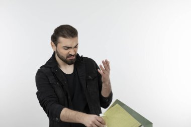 Beyaz bir duvarın üzerinde alışveriş torbası tutan genç yakışıklı bir adam. Yüksek kalite fotoğraf