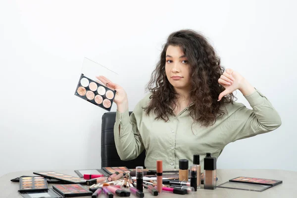 Mujer Joven Sentada Escritorio Con Personal Maquillaje Mostrando Pulgar Hacia — Foto de Stock