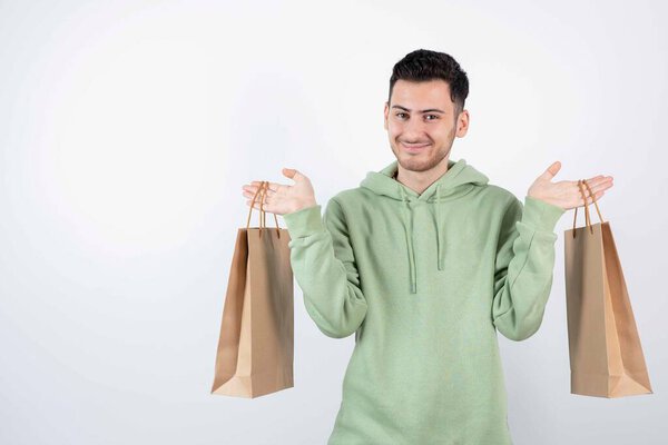 Handsome man in green hoodie holding paper bags. High quality photo