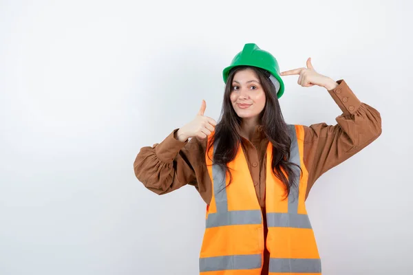 Ingenieurin Orangefarbener Weste Zeigt Auf Grünen Hut Und Zeigt Daumen — Stockfoto