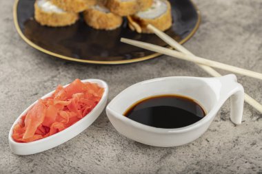 Siyah suşi ruloları ve taş bir masaya yerleştirilmiş zencefil dilimleri. Yüksek kalite fotoğraf