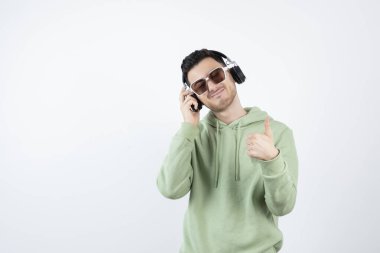 Kulaklıklı genç yakışıklı bir adamın başparmak kaldırışı. Yüksek kalite fotoğraf