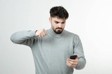 Akıllı telefonu beyaz duvara dayayan çekici adamın portresi. Yüksek kalite fotoğraf