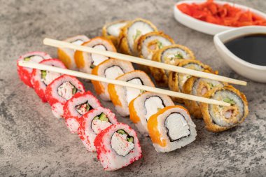 Taştan arka planda taze balıklı çeşitli suşi ruloları. Yüksek kalite fotoğraf