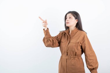 Beyaz duvara parmak doğrultan sevimli bir kadın modeli. Yüksek kalite fotoğraf