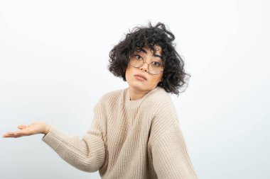 Gözlüklü güzel kıvırcık kadın avuçlarıyla bir şey gösteriyor. Yüksek kalite fotoğraf