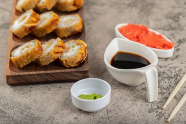 Wasabi, soya sosu ve taş bir masaya konmuş zencefil dilimli taze suşi ruloları. Yüksek kalite fotoğraf