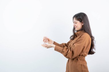 Beyazın üzerinde bir bardak su tutan gülümseyen bir kadın resmi. Yüksek kalite fotoğraf