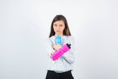 Beyaz arka planda plastik şişelerle poz veren süveter giyen kız