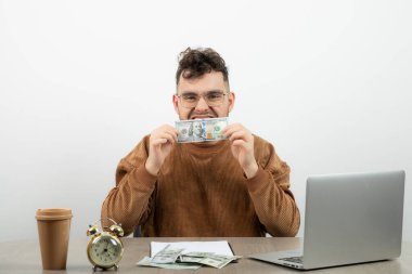 Genç yakışıklı işadamı masasında oturuyor ve elinde para var. Yüksek kalite fotoğraf