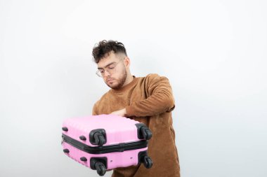 Çekici bir erkek modelin portresi ayakta ve pembe seyahat çantası taşıyor. Yüksek kalite fotoğraf