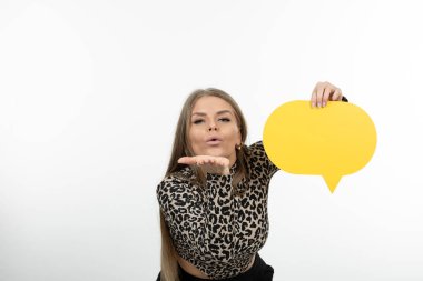 Hava öpücüğü veren ve sarı konuşma balonu tutan hoş görünümlü bir kadın. Yüksek kalite fotoğraf