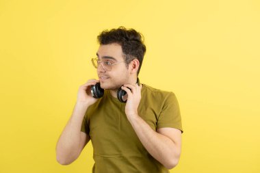Sarı duvarın üzerinde duran kulaklıklı yakışıklı bir adam resmi. Yüksek kalite fotoğraf