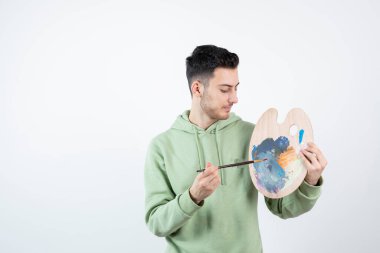 Kapüşonlu genç adamın portresi paletten renkleri alıyor. Yüksek kalite fotoğraf