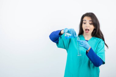 Beyaz duvar üzerinde kimyasal matara deneyleri yapan kadın bir laboratuvar çalışanı. Yüksek kalite fotoğraf