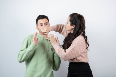 Esmer kadın, genç erkek mankene elleriyle ağzını kapatıyor. Yüksek kalite fotoğraf