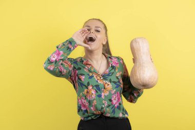 Sarı duvara taze tereyağlı kabak tutan bir kadın resmi. Yüksek kalite fotoğraf
