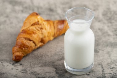 Lezzetli tereyağlı kruvasan ve taş masaya bir sürahi taze süt. Yüksek kalite fotoğraf