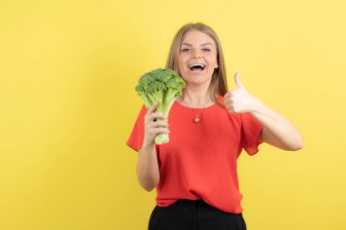 Büyük yeşil brokolisi olan güzel bir kadın modelin başparmağı görünüyor. Yüksek kalite fotoğraf