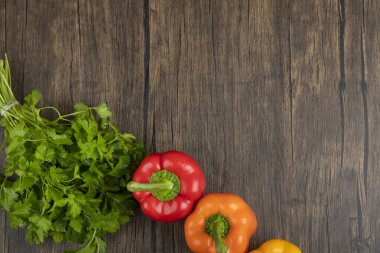 Ahşap arka planda renkli dolmalık biber ve yeşil maydanoz yaprakları. Yüksek kalite fotoğraf