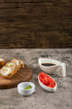 Kaya yüzeyinde somon ve sosla kızartılmış tahta suşi ruloları. Yüksek kalite fotoğraf