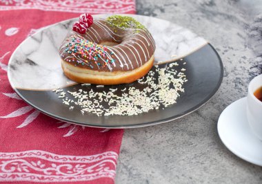 Renkli şekerli çikolatalı çörek ve bir fincan siyah çay. Yüksek kalite fotoğraf