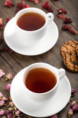 İki fincan çay, çiçekler ve ahşap arka planda yulaf ezmeli bisküviler. Yüksek kalite fotoğraf