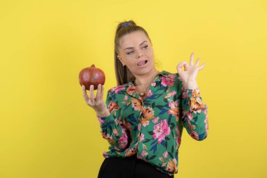 Sarı arka planda ok işareti veren narlı genç bir kadın resmi. Yüksek kalite fotoğraf