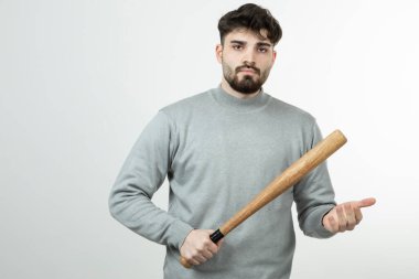 Beyzbol sopasını beyaz duvarda tutan yakışıklı adamın fotoğrafı. Yüksek kalite fotoğraf
