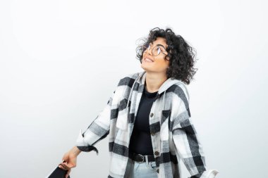 Gözlüklü kıvırcık saçlı, poz veren ve beyazın üzerinde duran bir kadın resmi. Yüksek kalite fotoğraf