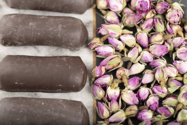 Bir bardak siyah çayın yanında çikolata çubukları ve gül çiçekleri olan bir tabak. Yüksek kalite fotoğraf