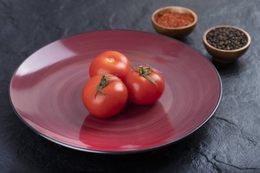 Biber taneli taze kırmızı domatesler ve siyah masaya konmuş toz. Yüksek kalite fotoğraf