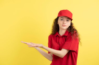 Kırmızı üniformalı genç bayan kurye açık alanda duruyor. Yüksek kalite fotoğraf