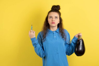 Patlıcan ve şırınga tutan kıvırcık bir kız resmi. Yüksek kalite fotoğraf