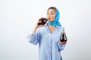 Elinde pişmemiş patlıcan tutan mavi şallı genç bir kadının portresi. Yüksek kalite fotoğraf