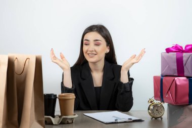 İş yerinde elinde hediyelerle oturan iş kadınının portresi.