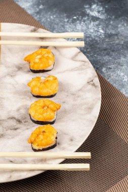 Karidesli suşi rulosu ve tabağa konmuş tek kullanımlık tahta çubuklar. Yüksek kalite fotoğraf