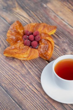 Kırmızı ahududu ve ahşap yüzeyde bir fincan çay ile nefis puf böreği. Yüksek kalite fotoğraf