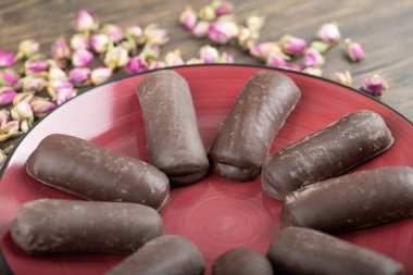 Tatlı çikolatalı kekler ve ahşap arka planda güller olan kırmızı tabak. Yüksek kalite fotoğraf