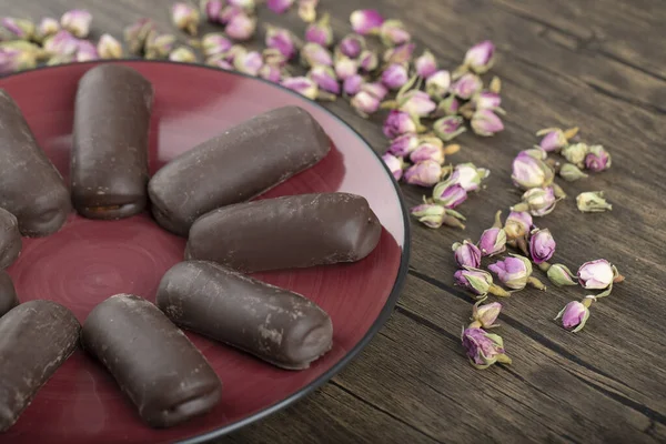 Kırmızı tabakta çikolatalı kekler ve ahşap arka planda güller. Yüksek kalite fotoğraf