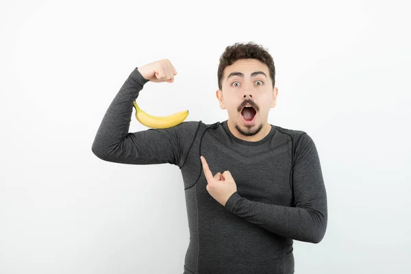 Joven Apuesto Deportista Apuntando Plátano Sobre Una Pared Blanca Foto —  Fotos de Stock