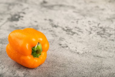 Taş zeminde su damlaları olan turuncu taze dolmalık biber. Yüksek kalite fotoğraf