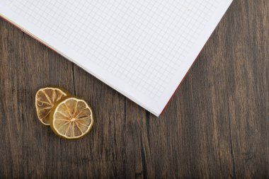 Dried lemon slices with white notebook placed on wooden table. High quality photo
