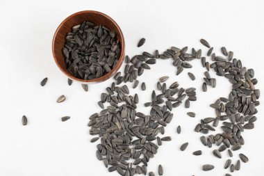 Beyaz arka plana yerleştirilmiş ayçiçeği tohumlarıyla dolu tahta bir kase. Yüksek kalite fotoğraf